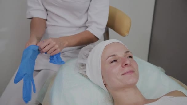 Профессиональный косметолог носит синие резиновые перчатки для процедуры . — стоковое видео