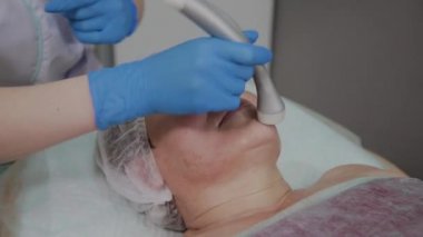 Profesyonel kozmetoloji ofisinde mikroakımlı yaşlı bir kadın için işlem yapar.