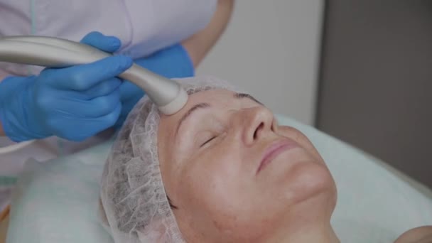 Professionele cosmetoloog voert de procedure voor een oudere vrouw met micro stromingen in het cosmetologie kantoor. — Stockvideo