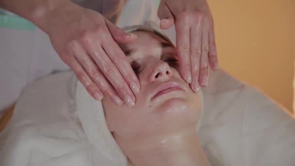 Professionele schoonheidsspecialiste maakt een complexe massage aan een jong meisje in het cosmetologie kantoor. — Stockvideo