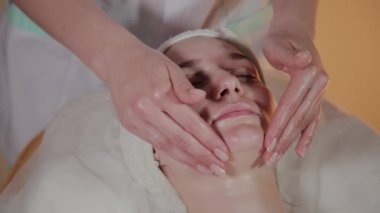 Profesyonel güzellik kozmetoloji ofisinde genç bir kız için karmaşık bir masaj yapar.