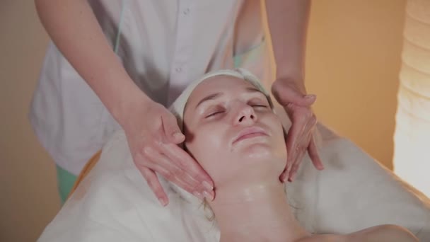 Professionele schoonheidsspecialiste maakt een complexe massage aan een jong meisje in het cosmetologie kantoor. — Stockvideo