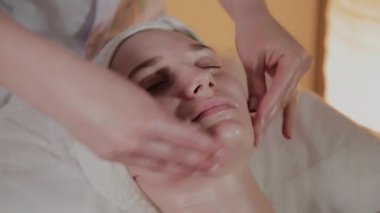 Profesyonel güzellik kozmetoloji ofisinde genç bir kız için karmaşık bir masaj yapar.