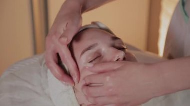 Profesyonel güzellik kozmetoloji ofisinde genç bir kız için karmaşık bir masaj yapar.