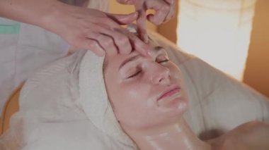 Profesyonel güzellik kozmetoloji ofisinde genç bir kız için karmaşık bir masaj yapar.