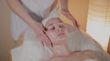 Profesyonel güzellik kozmetoloji ofisinde genç bir kız için karmaşık bir masaj yapar.