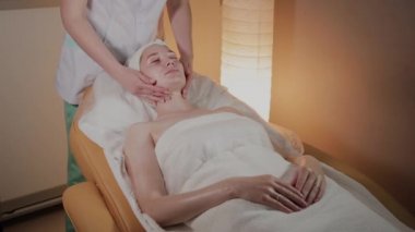 Profesyonel güzellik kozmetoloji ofisinde genç bir kız için karmaşık bir masaj yapar.