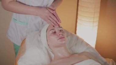Profesyonel güzellik kozmetoloji ofisinde genç bir kız için karmaşık bir masaj yapar.