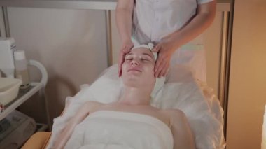 Profesyonel güzellik kozmetoloji ofisinde genç bir kız için karmaşık bir masaj yapar.