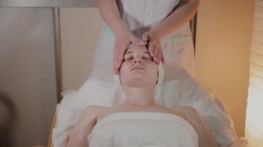 Profesyonel güzellik kozmetoloji ofisinde genç bir kız için karmaşık bir masaj yapar.
