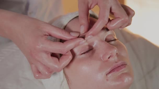 Esthéticienne professionnelle fait un massage complexe à une jeune fille dans le bureau de cosmétologie . — Video