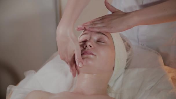 Professionele schoonheidsspecialiste maakt een complexe massage aan een jong meisje in het cosmetologie kantoor. — Stockvideo