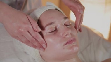 Profesyonel güzellik kozmetoloji ofisinde genç bir kız için karmaşık bir masaj yapar.