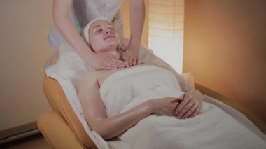 Profesyonel güzellik kozmetoloji ofisinde genç bir kız için karmaşık bir masaj yapar.