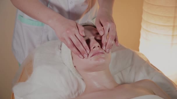 Professionele schoonheidsspecialiste maakt een complexe massage aan een jong meisje in het cosmetologie kantoor. — Stockvideo