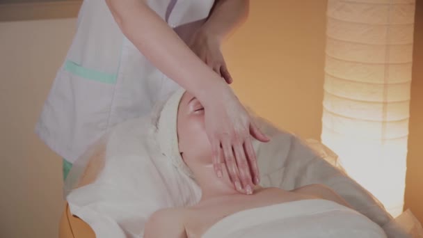 Professionele schoonheidsspecialiste maakt een complexe massage aan een jong meisje in het cosmetologie kantoor. — Stockvideo