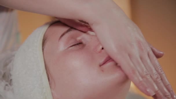 Professionelle Kosmetikerin macht eine komplexe Massage für ein junges Mädchen im Kosmetikbüro. — Stockvideo