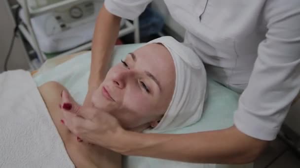 Hermosa mujer haciendo masaje facial en el salón de belleza . — Vídeo de stock