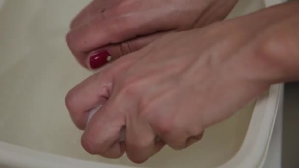 Der Prozess der Vorbereitung von Feuchttüchern zum Abwischen der Haut. Hände einer Kosmetikerin aus nächster Nähe. wässrige Lösung in einer weißen Tasse. Schönheitsoperation im Schönheitssalon — Stockvideo