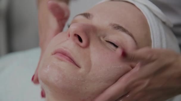 Hermosa mujer haciendo masaje facial en el salón de belleza . — Vídeos de Stock