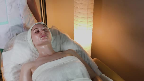 Esteticista profesional hace un masaje complejo a una joven en la oficina de cosmetología . — Vídeos de Stock