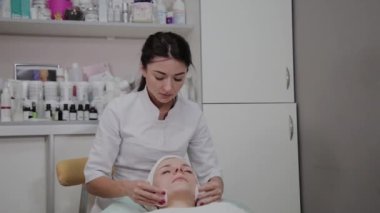 Güzel bir kadın güzellik prosedürü önce bir pamuk ped ile yüzünü ovuşturuyor.