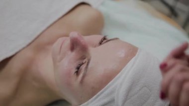 Profesyonel kozmetolojist güzellik salonunda yüz masajı yapıyor.