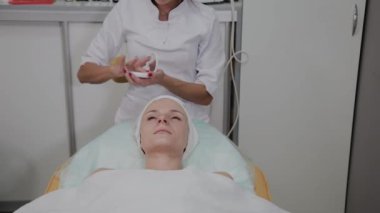 Profesyonel kozmetolojist kız yüzüne nemlendirici uygular.