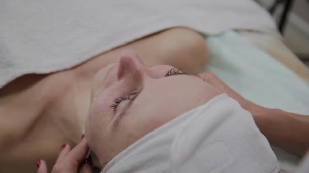 Une belle esthéticienne se frotte le visage avec un coton avant la procédure . — Video