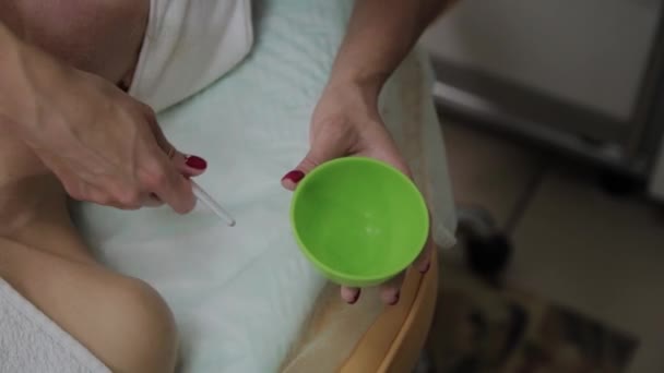 Профессиональный косметолог надевает маску на лицо пациента . — стоковое видео
