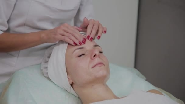 Profesyonel kozmetolojist güzellik salonunda yüz masajı yapıyor. — Stok video