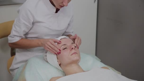 Professionele cosmetoloog doet gezichtsmassage in de schoonheidssalon. — Stockvideo