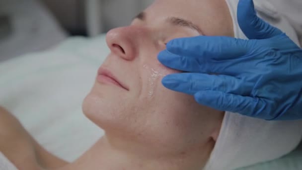 Cosmetologist profissional aplica o soro à cara dos pacientes . — Vídeo de Stock
