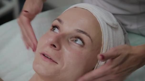Professionelle Kosmetikerin trägt Feuchtigkeitscreme auf Mädchengesicht auf. — Stockvideo