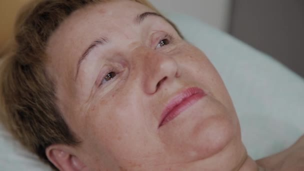 En äldre kvinna ljuger på en soffa i en kosmetika klinik. — Stockvideo