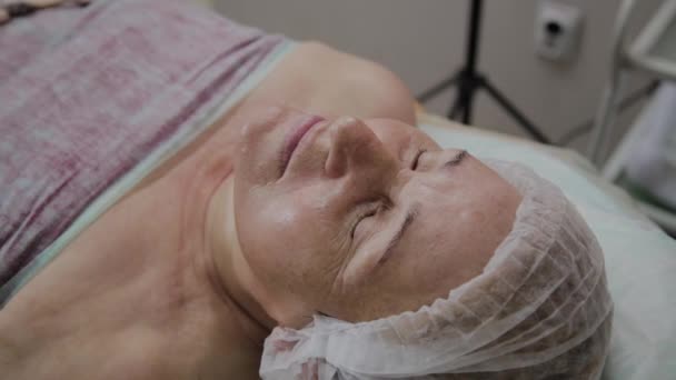 Пожилая женщина лежит на диване в косметологической клинике . — стоковое видео