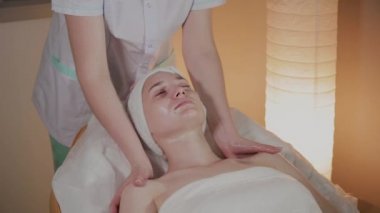 Profesyonel güzellik kozmetoloji ofisinde genç bir kız için karmaşık bir masaj yapar.