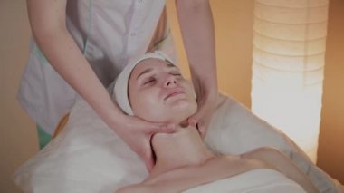 Profesyonel güzellik kozmetoloji ofisinde genç bir kız için karmaşık bir masaj yapar.