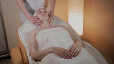 Profesyonel güzellik kozmetoloji ofisinde genç bir kız için karmaşık bir masaj yapar.