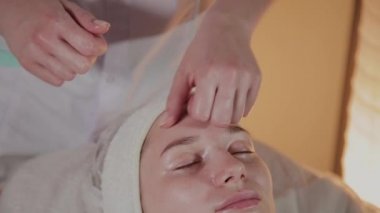 Profesyonel güzellik kozmetoloji ofisinde genç bir kız için karmaşık bir masaj yapar.
