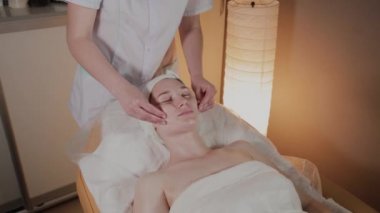 Profesyonel güzellik kozmetoloji ofisinde genç bir kız için karmaşık bir masaj yapar.