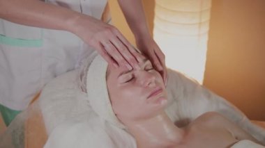 Profesyonel güzellik kozmetoloji ofisinde genç bir kız için karmaşık bir masaj yapar.