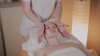 Profesyonel güzellik kozmetoloji ofisinde genç bir kız için karmaşık bir masaj yapar.