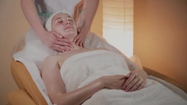 Profesyonel güzellik kozmetoloji ofisinde genç bir kız için karmaşık bir masaj yapar.