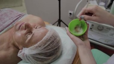 Kadın kozmetoloji stetik kozmetoloji kliniğinde makyaj maskesi karıştırır.