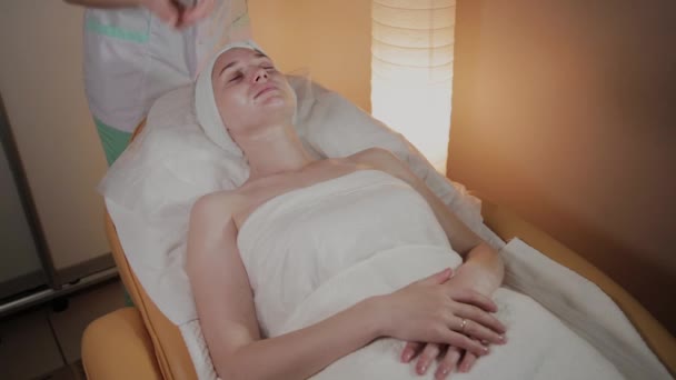 Professionele cosmetoloog past massage crème toe op het lichaam van een jong meisje in de schoonheidssalon. — Stockvideo