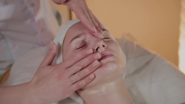 Esthéticienne professionnelle fait un massage complexe à une jeune fille dans le bureau de cosmétologie . — Video