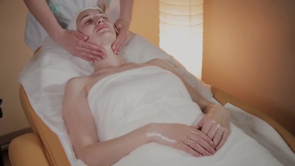 Professionele schoonheidsspecialiste maakt een complexe massage aan een jong meisje in het cosmetologie kantoor. — Stockvideo