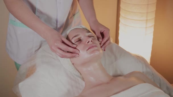 Professionele schoonheidsspecialiste maakt een complexe massage aan een jong meisje in het cosmetologie kantoor. — Stockvideo