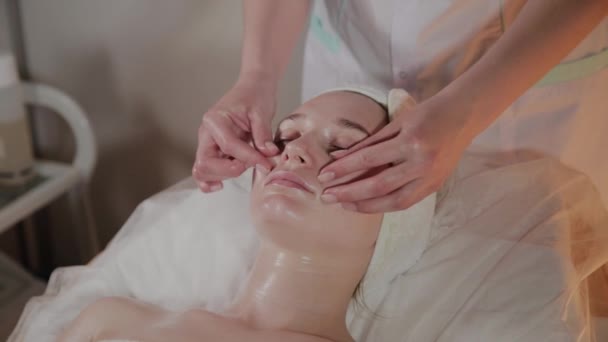 Professionele schoonheidsspecialiste maakt een complexe massage aan een jong meisje in het cosmetologie kantoor. — Stockvideo